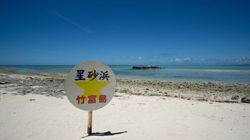 Information sign on beach against sky