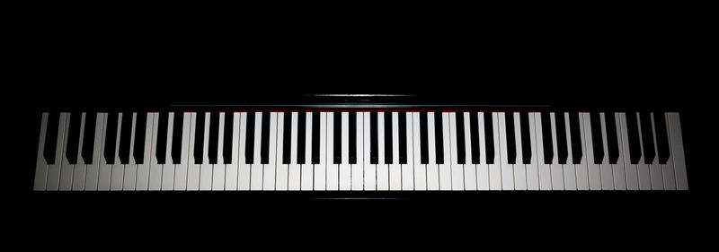 Close-up of piano keys against black background