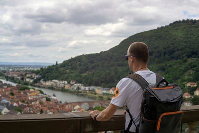 Rear view of man looking at cityscape against sky