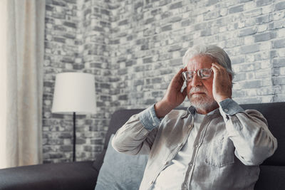 Side view of young man using mobile phone while sitting on sofa at home