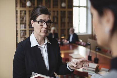 Confident lawyer discussing with female colleague in library