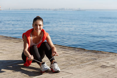 Portrait of smiling young woman sitting on shore