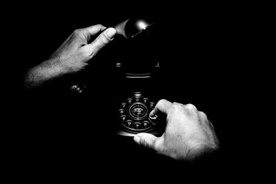 Close-up of hand holding camera over black background