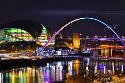 Illuminated bridge over river at night