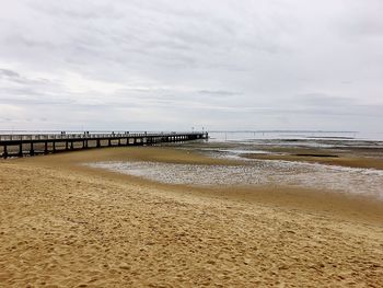 Pier at beach with sky in background