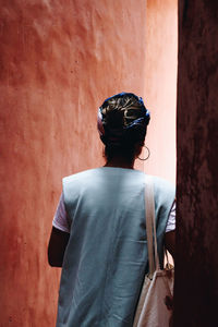 Rear view of man standing against yellow wall