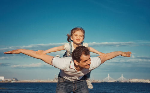 Portrait of boy with arms raised against sea against sky