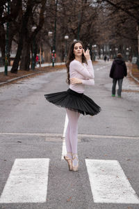 Full length portrait of woman on road in city