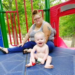 Portrait of happy mother with baby sitting outdoors