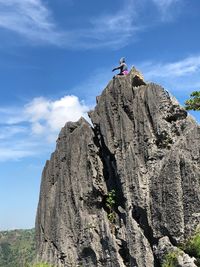 Low angle view of rocks on cliff against sky