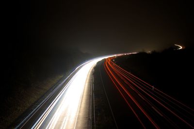 Light trails on road against sky at night