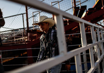 Young man looking away while standing on railing