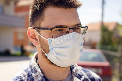 Close-up of man wearing flue mask standing outdoors