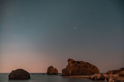 Rocks in sea against sky at night