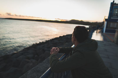 Man looking at sea against sky during sunset