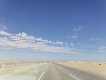 Empty road along landscape against blue sky