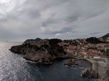 Buildings by sea against sky