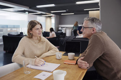 Two professionals working together in office cafeteria