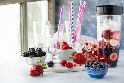 A blender container filled with ingredients used to make a mixed berry smoothie.