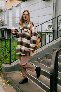 Portrait of woman standing against railing