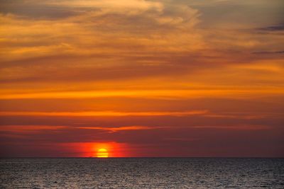 Scenic view of sea against dramatic sky during sunset