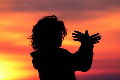 Silhouette woman standing against orange sky