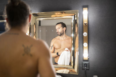 Rear view of shirtless man standing in bathroom