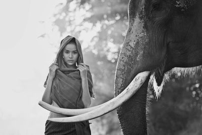 Portrait of smiling woman standing with elephant in temple