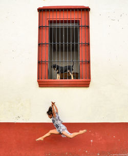 Man with red umbrella on wall