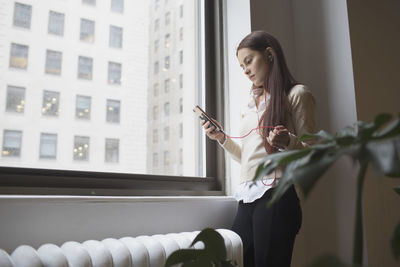 Young woman talking on smartphone through headphone