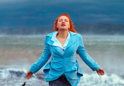 Carefree young woman with eyes closed standing at beach