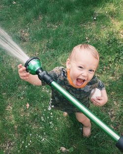 Portrait of little boy playing with garden hose in yard