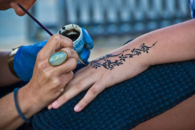 Cropped image of artist making henna tattoo on female hand