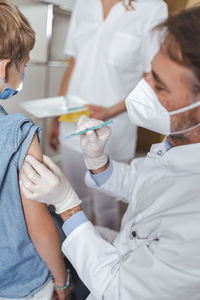 Doctor administering vaccine to boy at vaccination center