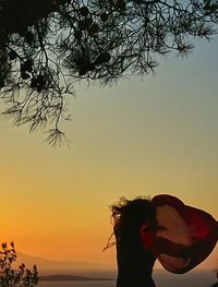 Silhouette woman by sea against sky during sunset