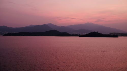 Scenic view of silhouette mountains by lake against romantic sky at sunset