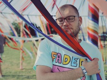 Full length of man holding multi colored stripes at summer festival 