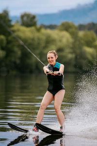 Full length of young woman holding umbrella while standing on lake