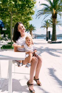Full length of mother and daughter sitting outdoors