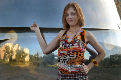 Portrait of young women standing against metal wall