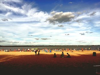 People relaxing at beach during sunny day