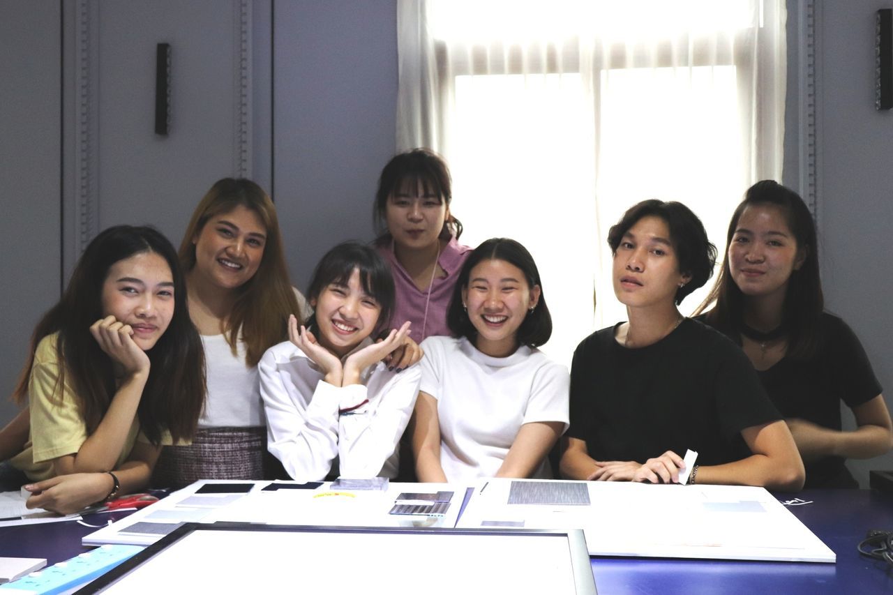 group of people, sitting, women, indoors, table, smiling, adult, front view, males, togetherness, people, real people, young women, men, group, young adult, education, portrait, book, coworker