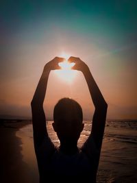 Silhouette man making heart shape against sky during sunset