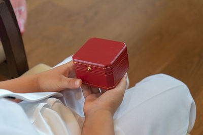 Midsection of child holding jewelry box while sitting at home