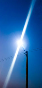 Low angle view of electricity pylon against blue sky