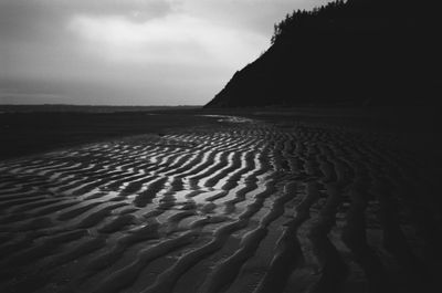 Scenic view of sand dune on beach against sky