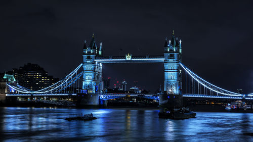 Illuminated bridge over river at night