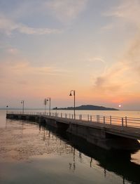 Pier over sea against sky during sunset