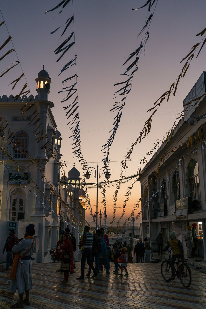 PEOPLE WALKING ON STREET AGAINST SKY AT SUNSET