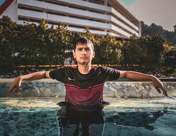 Young man with arms outstretched standing in water